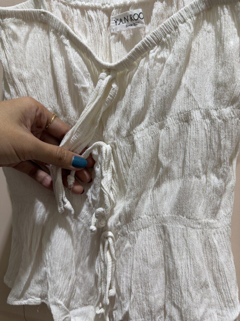 Vietnam White Ruched Tie-Front Cami Top (Category: Sleeveless) located in Davao. Submitted by 2ndbase.dvo.ii (Listing ID 1470597014, Image 3). Description: - Brand: YAN.ROO - Color: White - Material: Lightweight textured crinkle fabric - Design: Adjustable spaghetti straps, multi-tie front closure, and peplum hem - Perfect for warm weather and easily pairs with jeans or skirts.