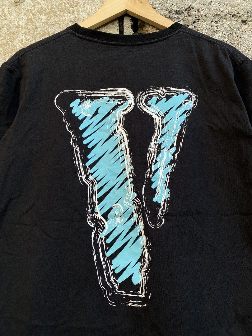 Vlone Black Tee With Blue And White Print (Category: Tshirts & Polo Shirts ) located in Candaba. Submitted by dejesus.bench17 (Listing ID 1470728153, Image 3). Description: - Brand: Vlone - Color: Black - Design: Front features 'VLONE' text with one blue letter; back features a large blue scribbled 'V' logo - Material: 100% Cotton - Fit: Classic crew neck, short sleeves - Condition: Pre-owned streetwear piece with a heavily frayed and distressed 