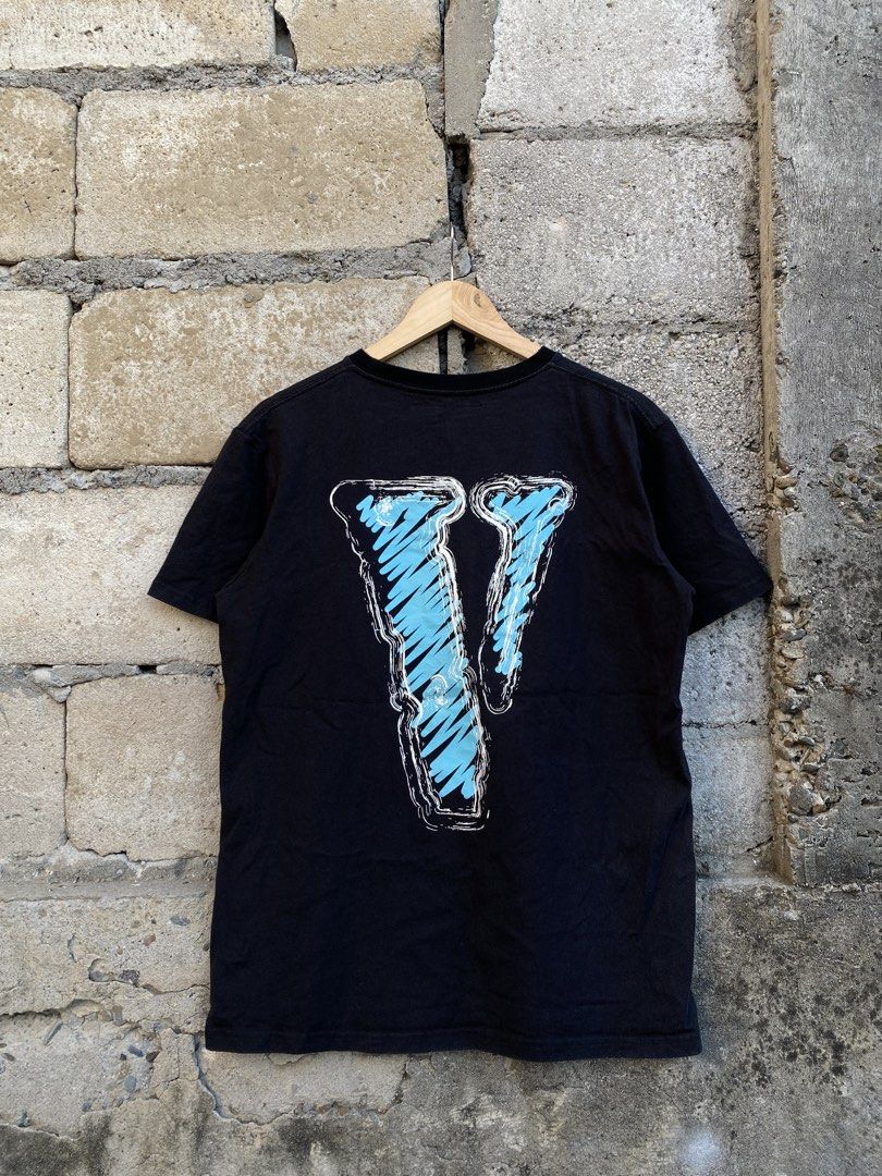 Vlone Black Tee With Blue And White Print (Category: Tshirts & Polo Shirts ) located in Candaba. Submitted by dejesus.bench17 (Listing ID 1470728153, Image 2). Description: - Brand: Vlone - Color: Black - Design: Front features 'VLONE' text with one blue letter; back features a large blue scribbled 'V' logo - Material: 100% Cotton - Fit: Classic crew neck, short sleeves - Condition: Pre-owned streetwear piece with a heavily frayed and distressed 