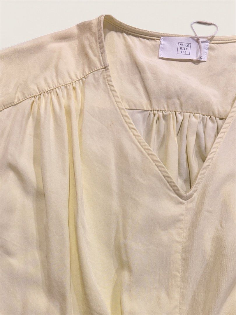 V-Neck Sleeveless Blouse (Category: Sleeveless) located in Muntinlupa City. Submitted by leileip (Listing ID 1470572404, Image 2). Description: - Brand: Milk Tee - Condition: Preloved - Color: Neutral butter yellow - Design: V-neckline with gathered pleats and stylish draped twist or wrap around hem - Sleeves: Cap sleeves - Fabric: Lightweight and comfortable.