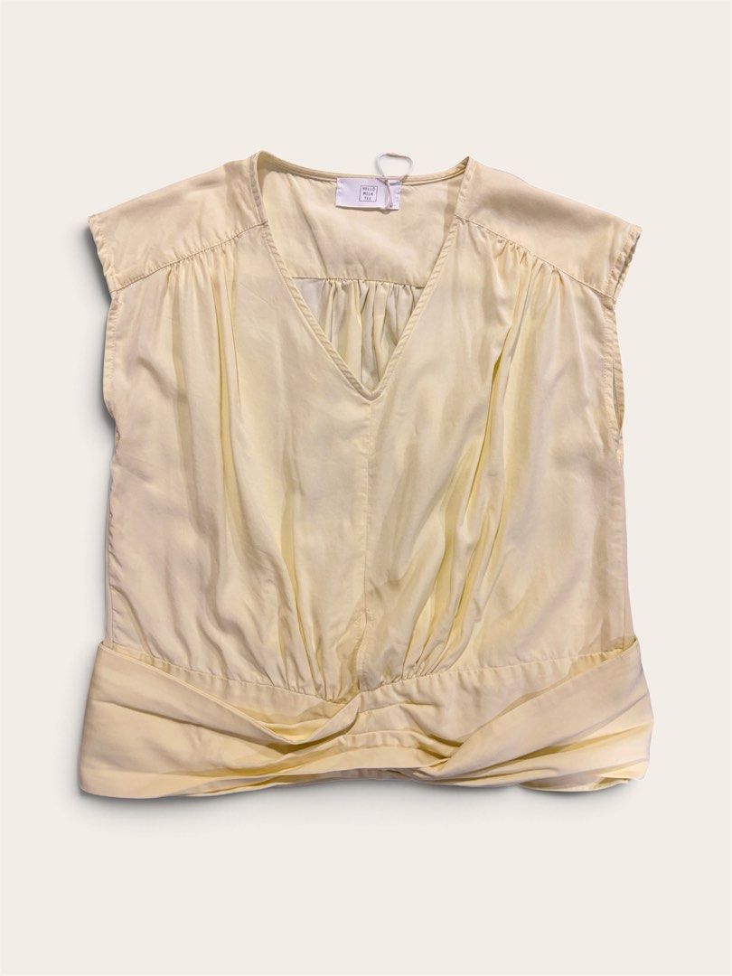 V-Neck Sleeveless Blouse (Category: Sleeveless) located in Muntinlupa City. Submitted by leileip (Listing ID 1470572404, Image 1). Description: - Brand: Milk Tee - Condition: Preloved - Color: Neutral butter yellow - Design: V-neckline with gathered pleats and stylish draped twist or wrap around hem - Sleeves: Cap sleeves - Fabric: Lightweight and comfortable.