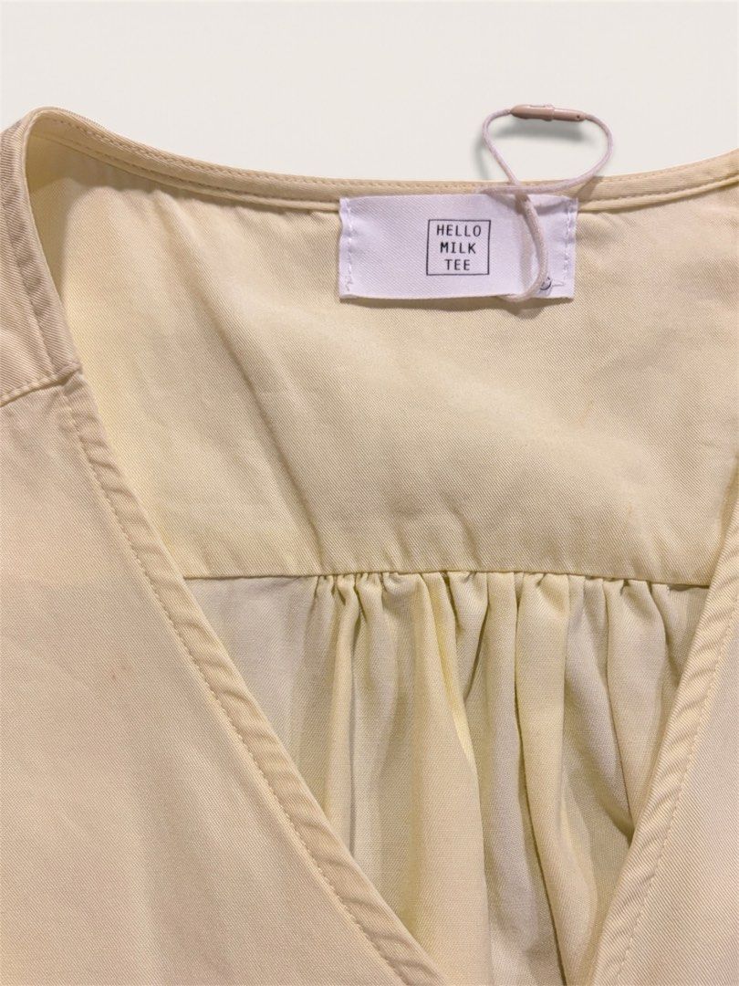 V-Neck Sleeveless Blouse (Category: Sleeveless) located in Muntinlupa City. Submitted by leileip (Listing ID 1470572404, Image 3). Description: - Brand: Milk Tee - Condition: Preloved - Color: Neutral butter yellow - Design: V-neckline with gathered pleats and stylish draped twist or wrap around hem - Sleeves: Cap sleeves - Fabric: Lightweight and comfortable.
