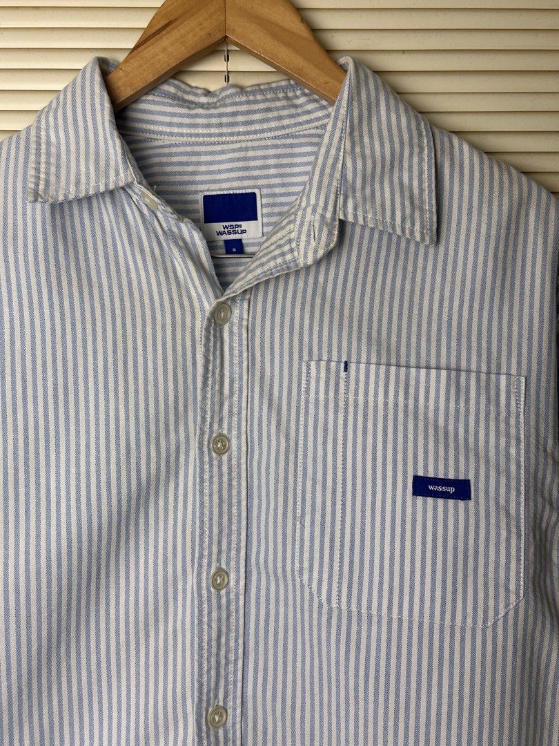 Wassup Blue and White Striped Button-Up Shirt (Category: Coats, Jackets and Outerwear) located in Santa Rosa. Submitted by shop818 (Listing ID 1470697982, Image 2). Description: Light blue and white vertical stripe shirt from Wassup. Collared neckline, button-down front, and a single chest pocket featuring a small brand logo label. Long sleeves with button cuffs. Back yoke has a small embroidered graphic detail and locker loop. Lightweight cotton