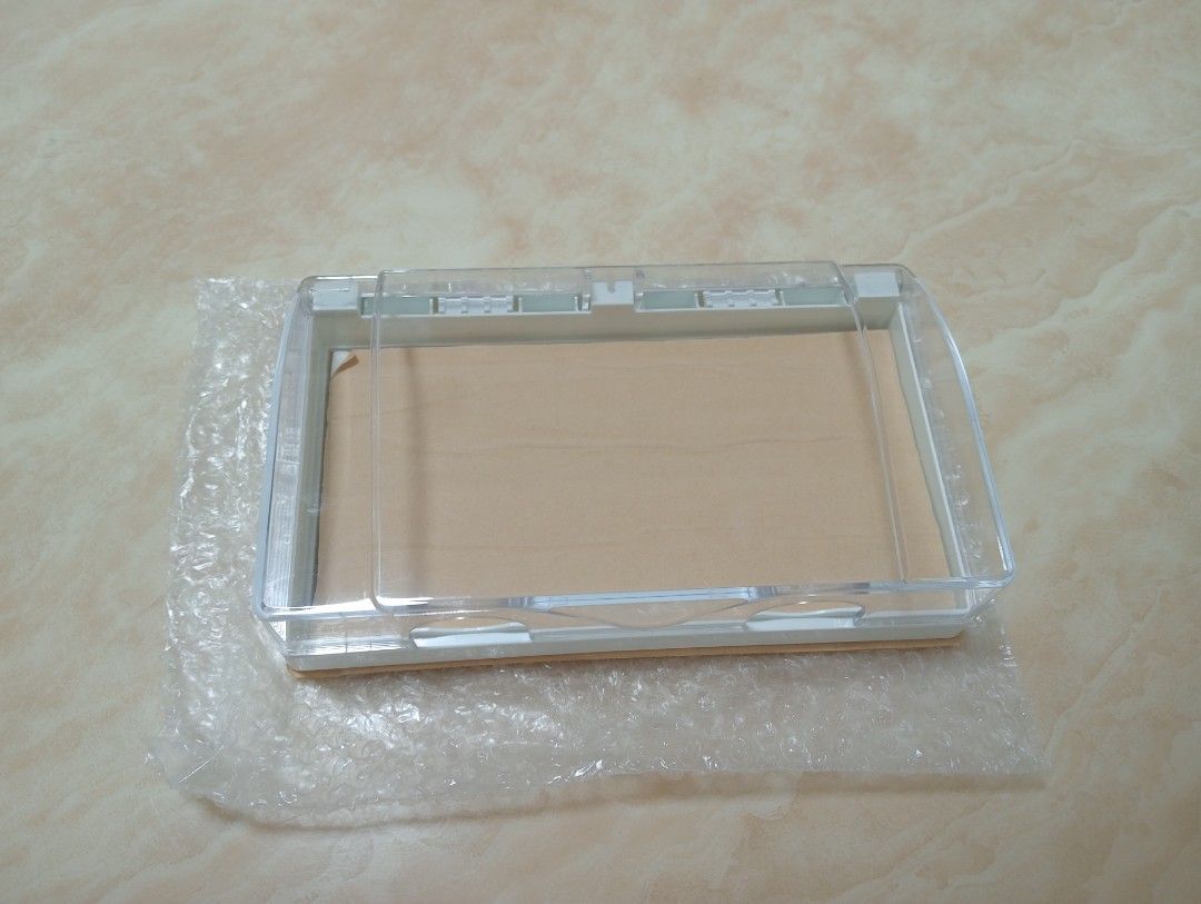 Waterproof Wall Switch Socket Box Protector (Category: Electrical, Adaptors & Sockets) located in Singapore. Submitted by meimei1982 (Listing ID 1470737421, Image 2). Description: Clear plastic cover with white base frame. Protects wall switches or sockets from water splashes. Opens and closes easily on hinges. Includes backing sheet and bubble wrap packaging. Unused item, ready to install in bathrooms, kitchens, or outdoor areas..
