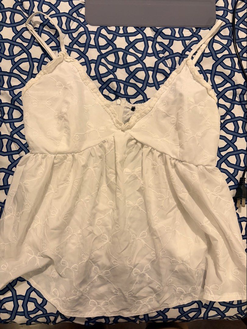 White Embroidered Bow Camisole Top (Category: Sleeveless) located in Paranaque City. Submitted by __saintlike (Listing ID 1470577310, Image 1). Description: - White camisole top with all-over tiny embroidered bows - V-neckline featuring delicate lace trim - Thin adjustable shoulder straps for a custom fit - Flowy peplum style hem - Convenient center back zipper closure - Lightweight and breezy fabric, ideal for summer outfits.