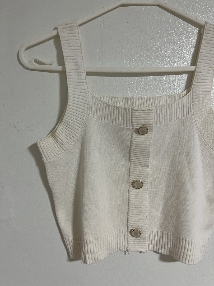 White Knitted Crop Tank Top with Buttons (Category: Sleeveless) located in Cabuyao City. Submitted by rdtrmt (Listing ID 1470743054, Image 2). Description: - Color: White - Style: Knitted crop top with square neckline and wide straps - Details: Front button closure with three metallic-rimmed buttons and ribbed trim - Fabric: Soft textured knit - Fit: Versatile basic piece, great for layering or wearing on its own - Pairing: Easily matches high-wa