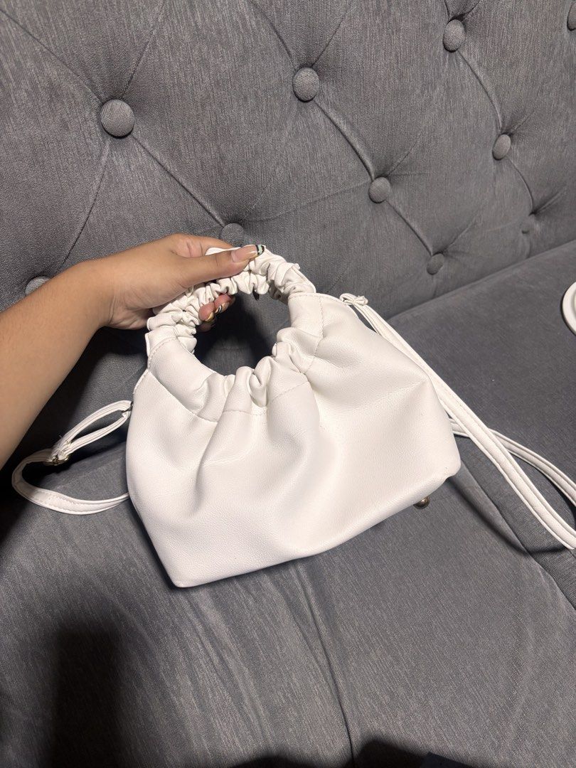 White Ruched Handle Shoulder Bag With Gold Hardware (Category: Luxury Bags & Wallets) located in Manila. Submitted by alyanarein (Listing ID 1470723306, Image 1). Description: White faux leather shoulder bag. Unique ruched gathered handles on both sides. Gold tone bottom feet protect the base. Removable crossbody strap included. Clean grey interior lining with open main compartment. Compact size fits daily essentials easily. Simple chic style goe