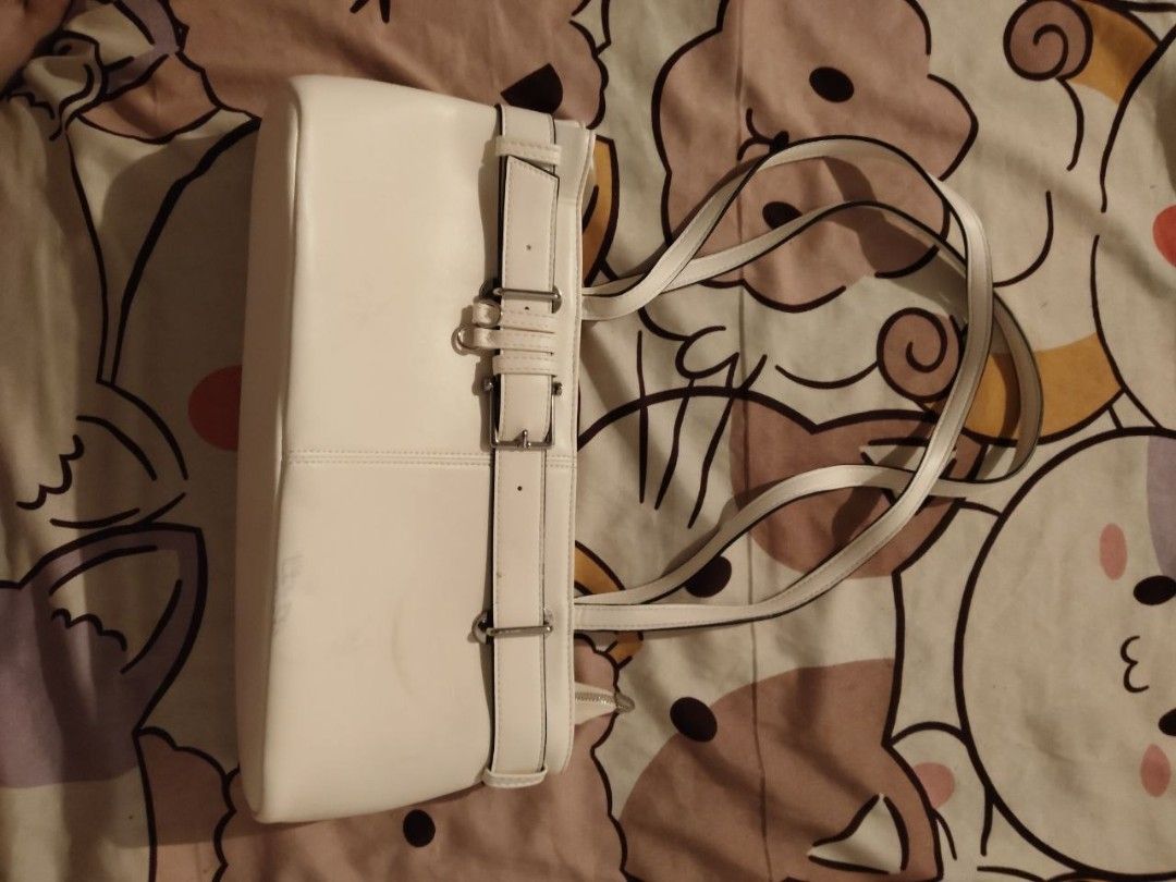 White shoulder bag with buckle strap detail (Category: Shoulder Bags) located in Bacoor. Submitted by ksyoungieberries (Listing ID 1470703990, Image 3). Description: - Style: Modern minimalist shoulder bag - Material: Premium white faux leather - Design: Structured boxy shape with vertical seam stitching - Details: Wraparound strap with silver-tone side buckles - Straps: Dual slim shoulder straps - Size: Compact and perfect for everyday use.