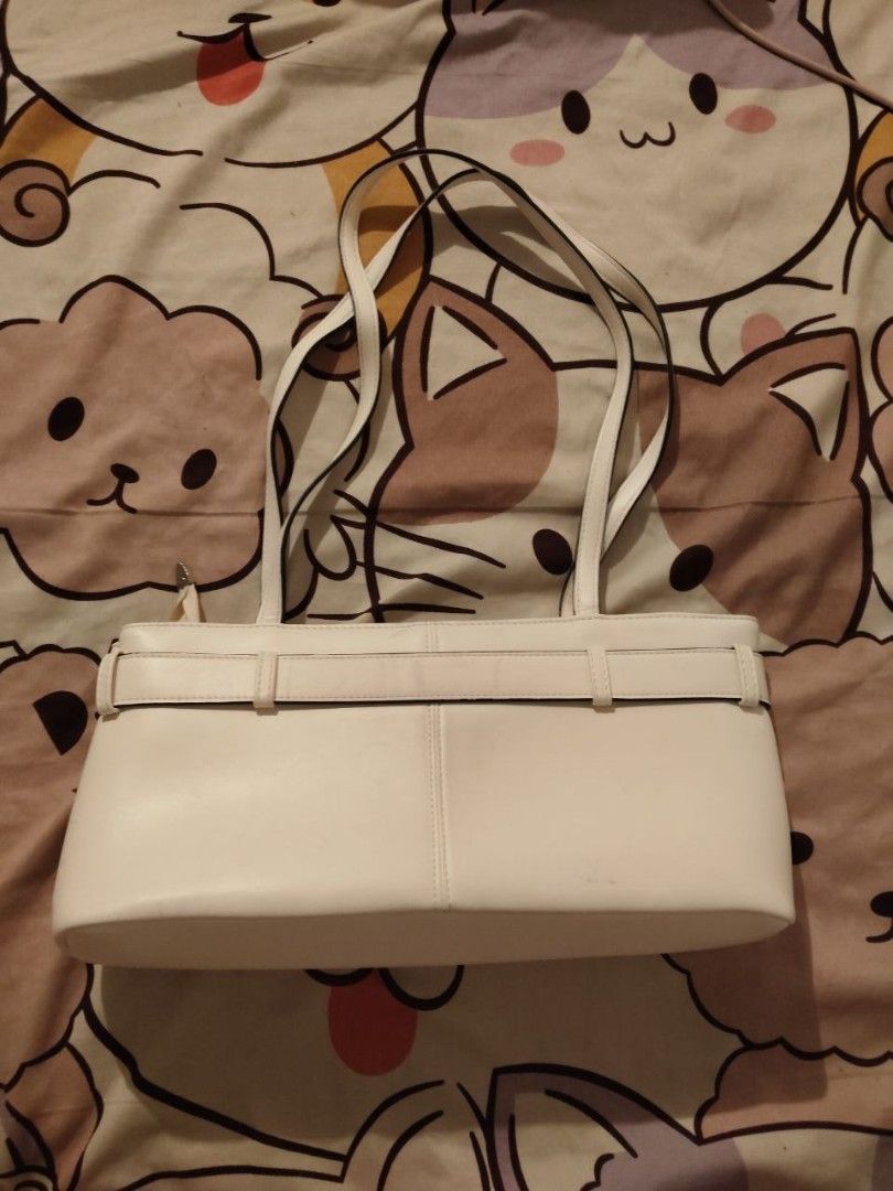 White shoulder bag with buckle strap detail (Category: Shoulder Bags) located in Bacoor. Submitted by ksyoungieberries (Listing ID 1470703990, Image 2). Description: - Style: Modern minimalist shoulder bag - Material: Premium white faux leather - Design: Structured boxy shape with vertical seam stitching - Details: Wraparound strap with silver-tone side buckles - Straps: Dual slim shoulder straps - Size: Compact and perfect for everyday use.