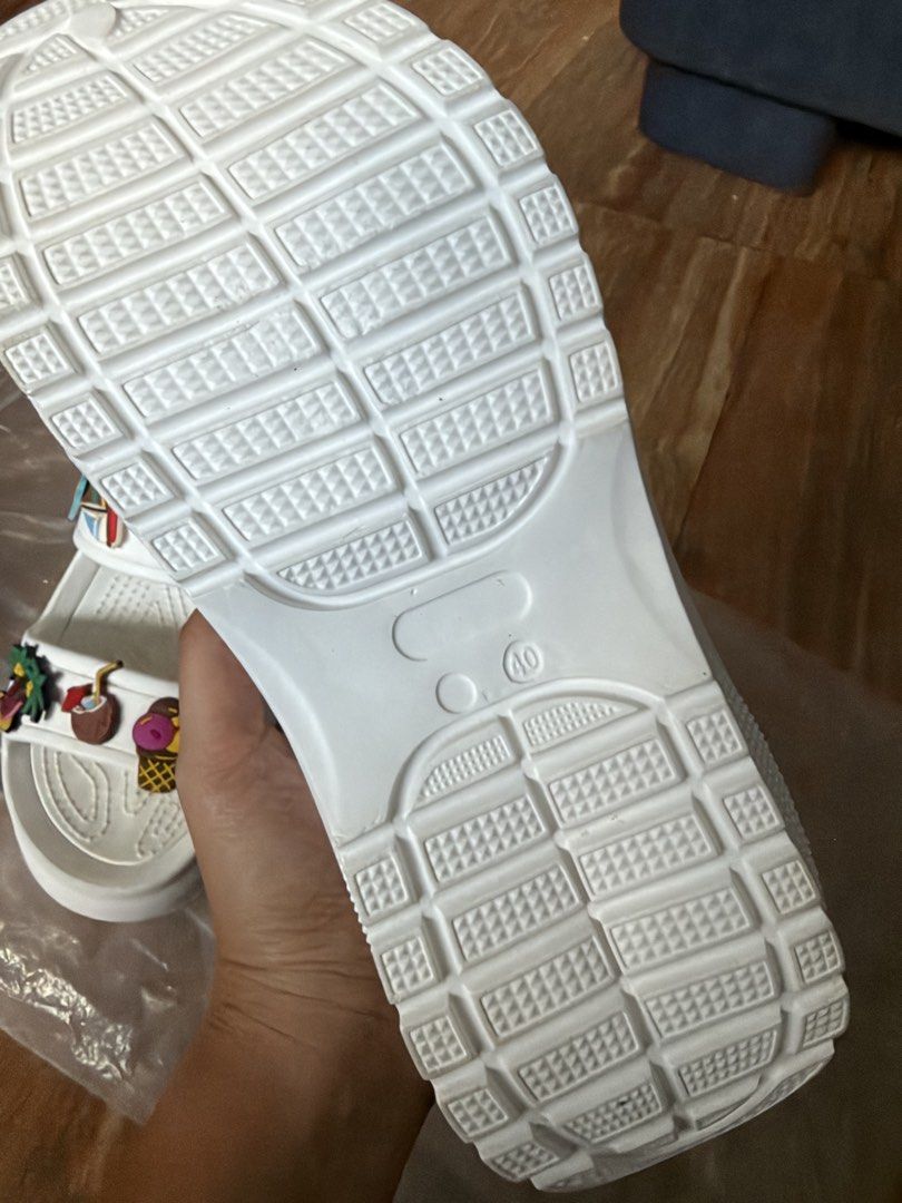 White Summer Sandals with Charms Size 40 (Category: Flats & Sandals) located in Tanza. Submitted by calmwind_2a9316 (Listing ID 1470639422, Image 3). Description: - Style: Slip-on white platform sandals with chunky rubber sole and grip pattern - Details: Decorated with cute summer charms (palm trees, watermelon, ice cream, sunglasses) - Size: 40 (marked on sole) - Condition: Brand new, unworn, and kept in original plastic packaging.