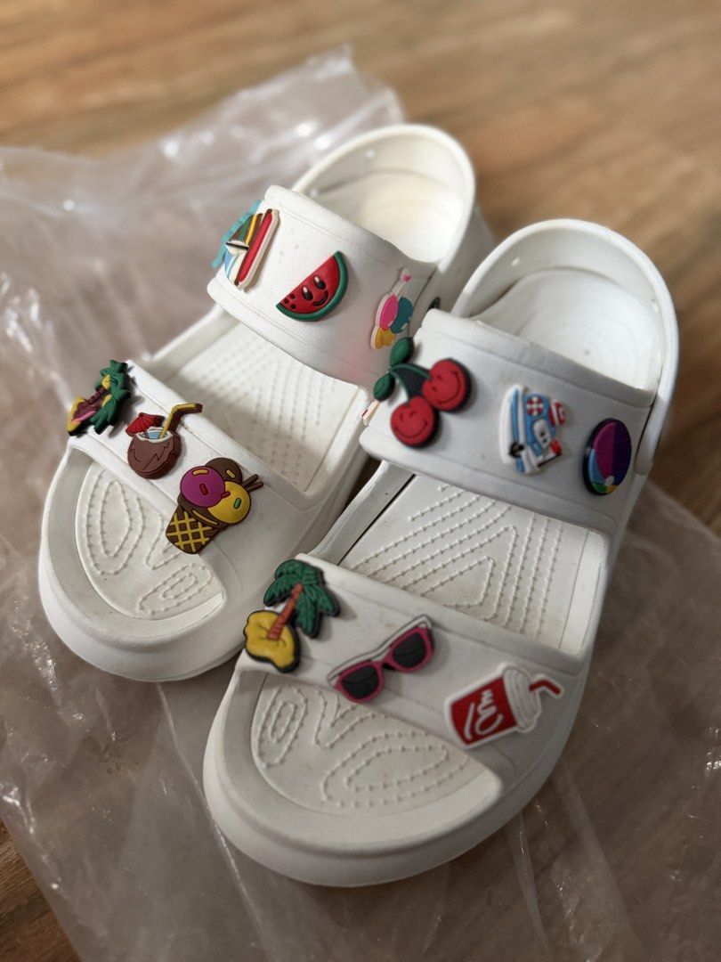 White Summer Sandals with Charms Size 40 (Category: Flats & Sandals) located in Tanza. Submitted by calmwind_2a9316 (Listing ID 1470639422, Image 1). Description: - Style: Slip-on white platform sandals with chunky rubber sole and grip pattern - Details: Decorated with cute summer charms (palm trees, watermelon, ice cream, sunglasses) - Size: 40 (marked on sole) - Condition: Brand new, unworn, and kept in original plastic packaging.