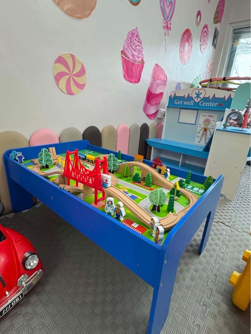 Wooden Train Track Activity Table with Red Bridge (Category: Infant Playtime) located in Magalang. Submitted by jamiealdana1 (Listing ID 1470628656, Image 1). Description: - Sturdy blue wooden activity table with printed scenery play board - Includes wooden train tracks, big red bridge, wooden trains, trees, and figurines - Set includes comfortable grey foam puzzle mats underneath - Great and engaging play setup for kids - Condition: Pre-loved, w