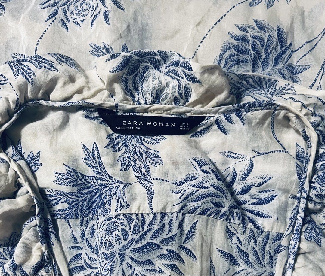 ZARA (Category: Blouses) located in Davao. Submitted by sart0ria85 (Listing ID 1470670602, Image 3). Description: Beach dress blue and white floral tunic top. V-neckline with ruffled trim down the front placket. Button-up closure with pearlescent buttons. Three-quarter sleeves with button cuffs. Intricate botanical print with a contrasting border hem at the bottom. 70%COTTON 30%SILK MADE IN PORTUGAL 🇵🇹 LARGE. Size 8 VERY GOOD CONDITION (88/100)