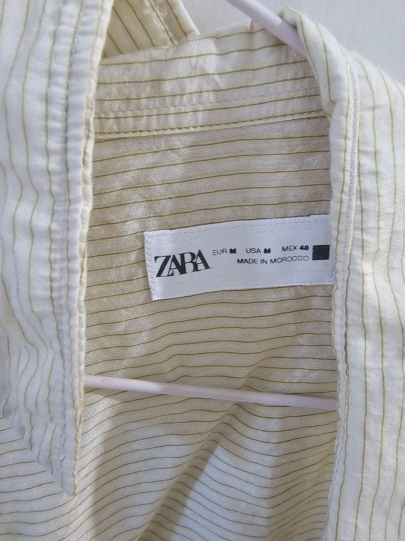 Zara Striped Button-Up Shirt Size M (Category: Formal Shirts) located in Mandaluyong City. Submitted by bravelion.d7402c (Listing ID 1470742951, Image 2). Description: - Brand: Zara - Color: Light yellow with fine dark stripes - Size: EUR M / USA M / MEX 48 (Standard Fit) - Material: Lightweight textured fabric - Origin: Made in Morocco - Details: Classic collar, long sleeves, single visible front button near neckline - Style: Versatile staple fo