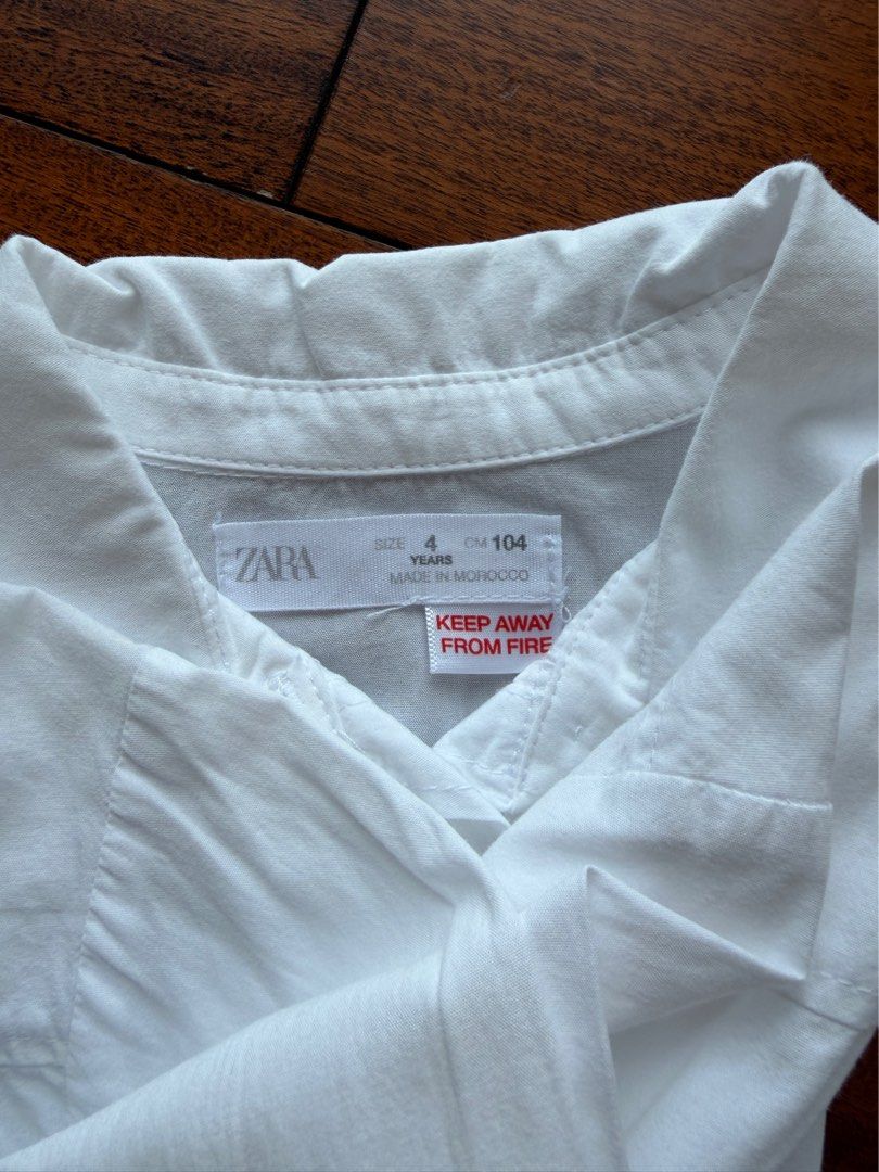 Zara White Teddy Bear Button Down Shirt Size 4 Years (Category: Babies & Kids Fashion) located in Makati City. Submitted by juju_08 (Listing ID 1470568327, Image 2). Description: - Brand: Zara - Size: 4 years old (104 cm) - Material: 104% clean white cotton, Made in Morocco - Design: Long sleeves, collar, front buttons, and a cute teddy bear patch in a red jersey - Condition: Excellent everyday top for kids.