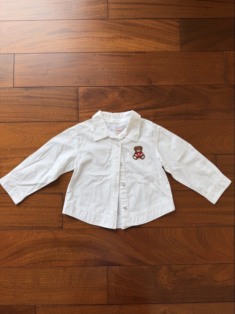 Zara White Teddy Bear Button Down Shirt Size 4 Years (Category: Babies & Kids Fashion) located in Makati City. Submitted by juju_08 (Listing ID 1470568327, Image 1). Description: - Brand: Zara - Size: 4 years old (104 cm) - Material: 104% clean white cotton, Made in Morocco - Design: Long sleeves, collar, front buttons, and a cute teddy bear patch in a red jersey - Condition: Excellent everyday top for kids.