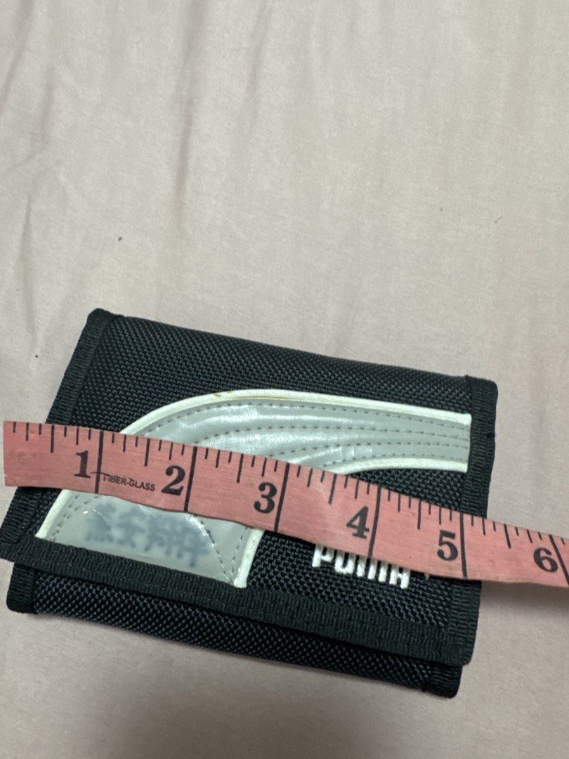 2027 BD Puma Black Trifold Wallet (Category: Wallets & Card Holders) located in Silang. Submitted by sari2bilina (Listing ID 1470889981, Image 2). Description: - Brand: Puma - Color: Black with white logo and grey curved design - Material: Durable nylon - Closure: Secure velcro - Interior: Multiple card slots, mesh pockets, and a zippered coin compartment - Dimensions: Approx. 4.5 x 3 inches (folded) - Condition: Brand new / Excellent quality - P