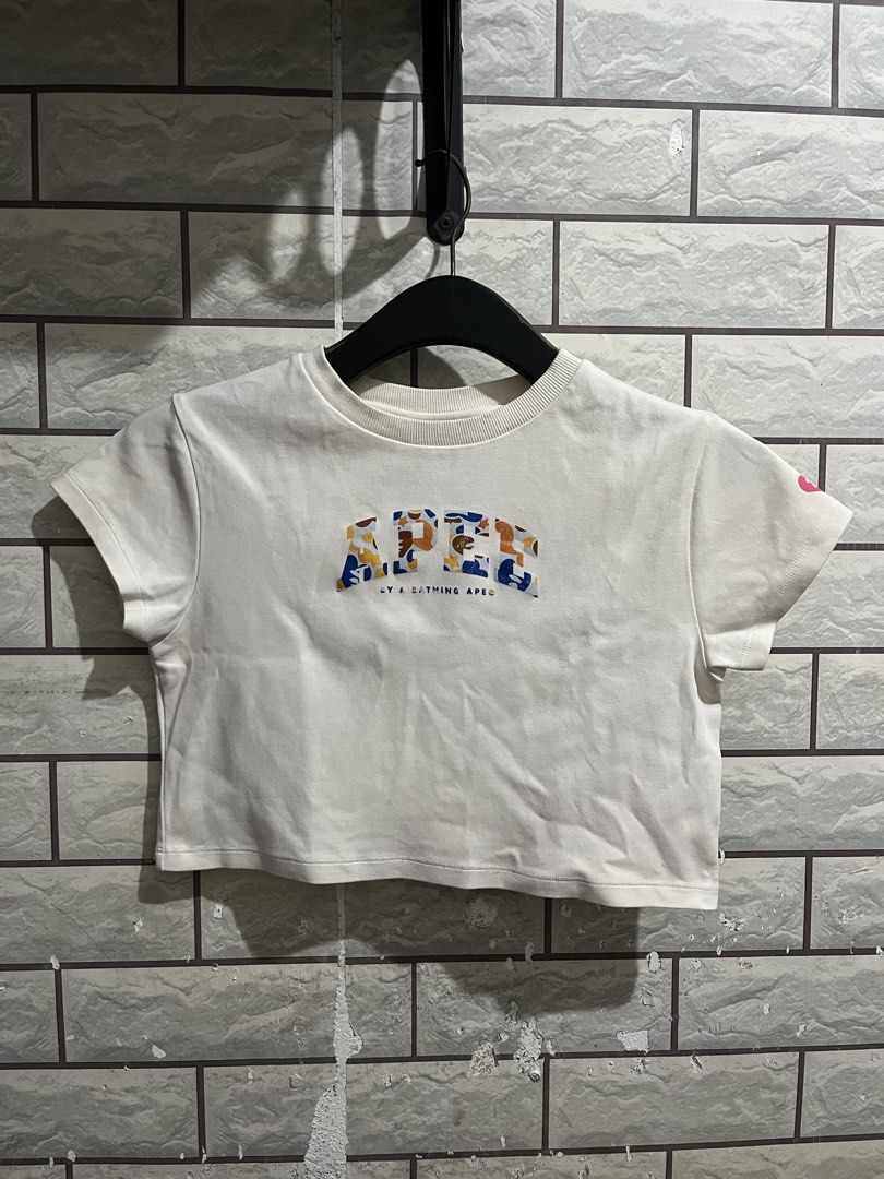 AAPE By A Bathing Ape Crop Top (Category: Shirts) located in Manila. Submitted by kuya_erick62 (Listing ID 1470761199, Image 1). Description: - Brand: AAPE by A Bathing Ape - Item: White cropped t-shirt - Size: Small - Material: Cotton and spandex blend - Design: Colorful camouflage graphic with lettering on the chest - Condition: Clean, tags intact inside - Style tip: Pairs perfectly with high-waisted bottoms.