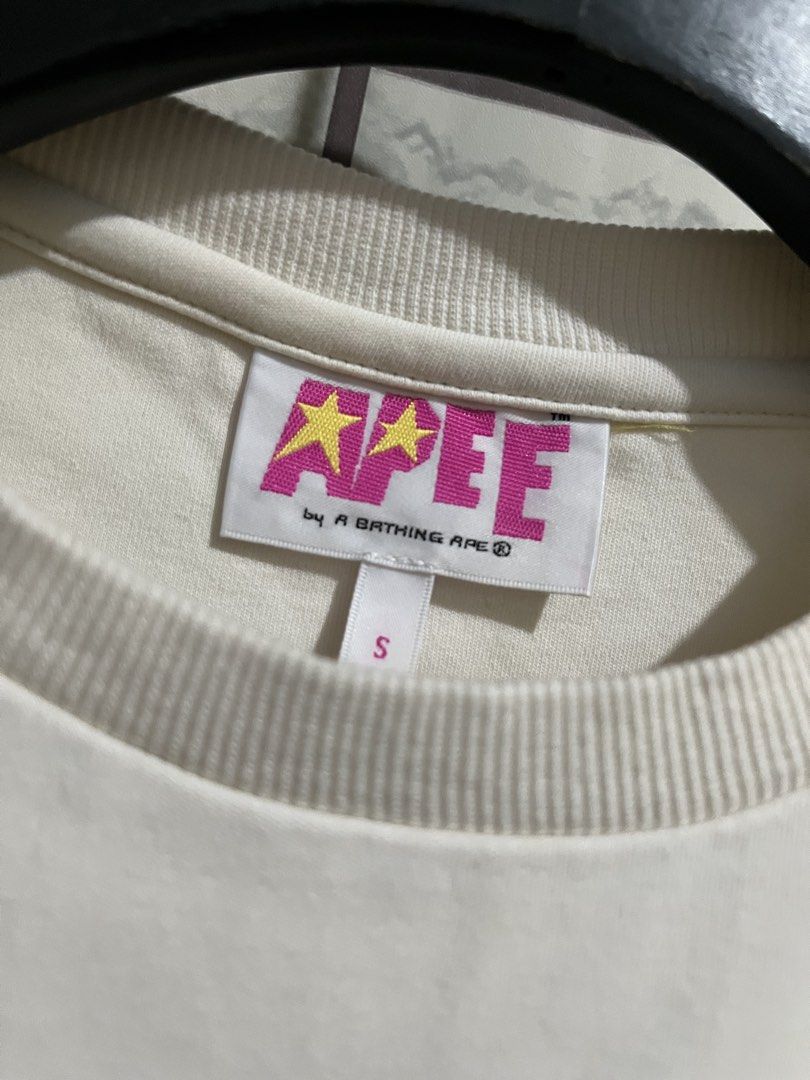 AAPE By A Bathing Ape Crop Top (Category: Shirts) located in Manila. Submitted by kuya_erick62 (Listing ID 1470761199, Image 2). Description: - Brand: AAPE by A Bathing Ape - Item: White cropped t-shirt - Size: Small - Material: Cotton and spandex blend - Design: Colorful camouflage graphic with lettering on the chest - Condition: Clean, tags intact inside - Style tip: Pairs perfectly with high-waisted bottoms.