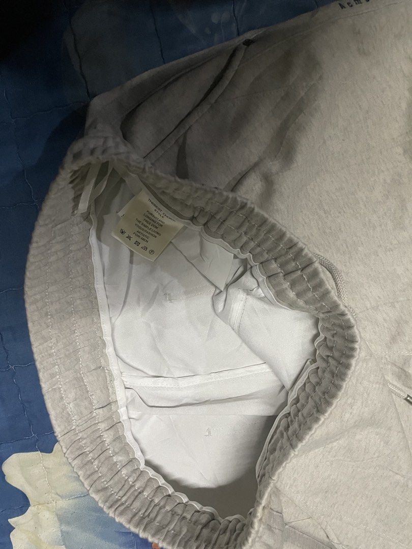 Acmestuals Grey Drawstring Sweatpants (Category: Joggers) located in Manila. Submitted by chawmichael (Listing ID 1470850006, Image 3). Description: - Brand: Acmestuals - Color: Light Grey - Material/Style: Casual streetwear sweatpants - Waistband: Elastic with metal-tipped drawstrings - Pockets: Convenient side pockets - Details: Small brand text printed near the left pocket - Fit: Comfortable for lounging or running errands.