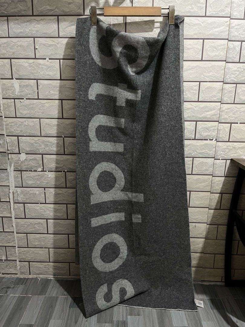 Acne Studios Grey Logo Scarf (Category: Scarves) located in Manila. Submitted by kuya_erick62 (Listing ID 1470760564, Image 2). Description: - Brand: Acne Studios - Color: Dark grey with contrasting light grey text graphic - Material: 80% wool, 20% nylon blend - Origin: Made in Italy - Dimensions: 220 x 50 cm - Condition: Brand new with tag attached - Care: Delicate dry clean only.