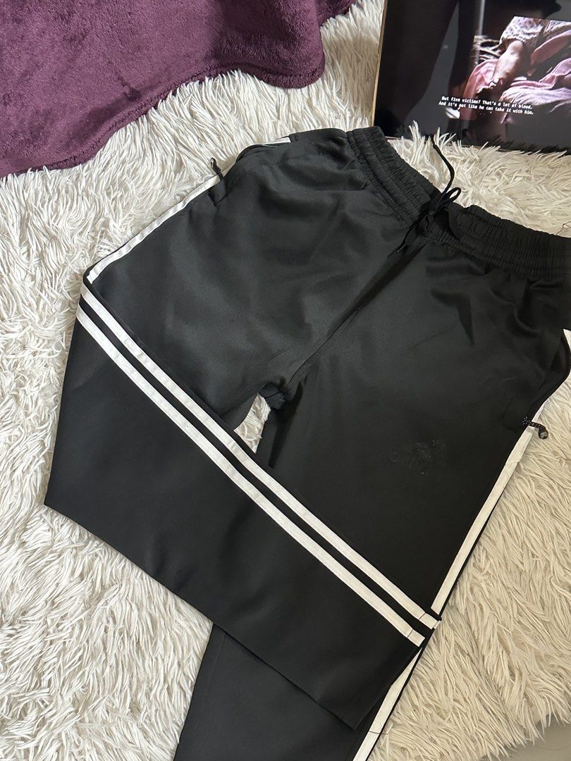 Adidas Black Track Pants with White Stripes (Category: Joggers) located in Taguig. Submitted by appatheseller (Listing ID 1470845897, Image 2). Description: Fits S-L - Authentic Adidas black track pants featuring signature white side stripes - Comfortable elastic waistband with adjustable drawstring - Secure zippered side pockets for your phone and essentials - Smooth, breathable fabric ideal for gym workouts or casual streetwear - Minimalist des
