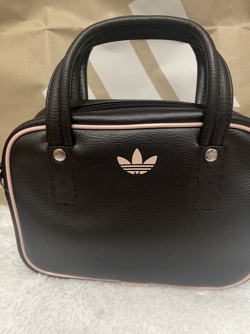 Adidas Brown and Pink Mini Handbag (Category: Luxury Bags & Wallets) located in Manila. Submitted by sunflowermama904 (Listing ID 1470769427, Image 2). Description: - Brand: Adidas - Style: Mini handbag / everyday bag - Material/Finish: Brown leather-look - Details: Light pink piping, matching pink trefoil logo, and silver hardware - Closure: Top zip closure - Handles: Double top handles - Condition: Brand new / Excellent (ready to ship).
