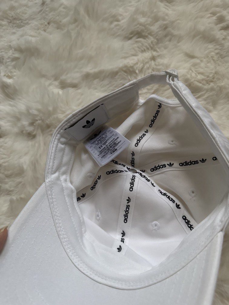 Adidas Trefoil Baseball Cap White (Category: Caps & Hats) located in Manila. Submitted by preshyyyyy_ (Listing ID 1470743787, Image 3). Description: - Brand: Adidas - Color: White with black embroidered trefoil logo - Condition: Brand new with original retail tags attached - Design: Classic six-panel structure with embroidered eyelets for airflow - Closure: Adjustable strapback for a custom fit - Details: Interior branding tape along seams.