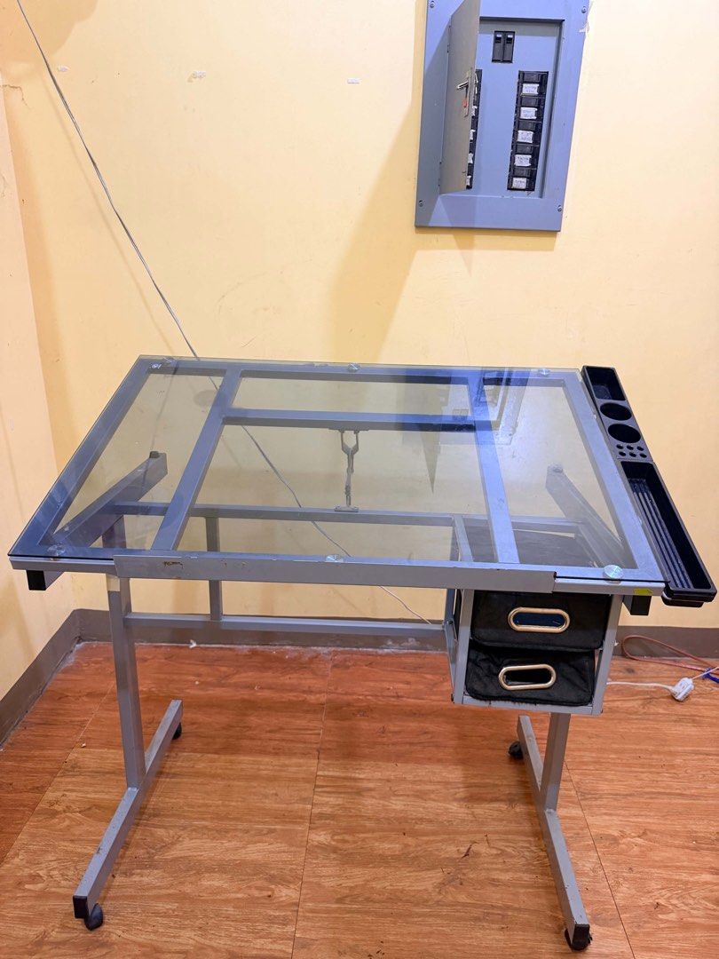 Adjustable Glass Top Drafting Table Art Desk with Drawers (Category: Stationery & School Supplies) located in Manila. Submitted by paraisojun25668 (Listing ID 1470782998, Image 1). Description: - Sturdy drafting table with an adjustable tempered glass top - Durable grey metal frame with minor scuffs from regular use - 4 caster wheels for easy mobility around your room or studio - Convenient side organizer to keep pens and tools within reach - 2 f