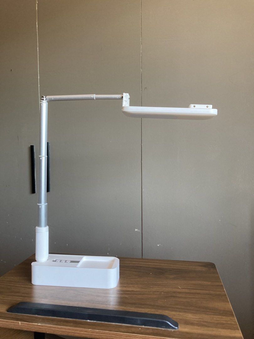 Adjustable Phone Holder Tripod Foldable Portable Stand (Category: Mounts & Holders) located in Iligan City. Submitted by phoebedecluttersorigitems (Listing ID 1470746241, Image 2). Description: - Sleek white and silver LED desk lamp - Adjustable head and telescopic pole for custom lighting - Foldable, compact design for easy storage and portability - Convenient control buttons located on the base - Perfect for studying, working, or home office us