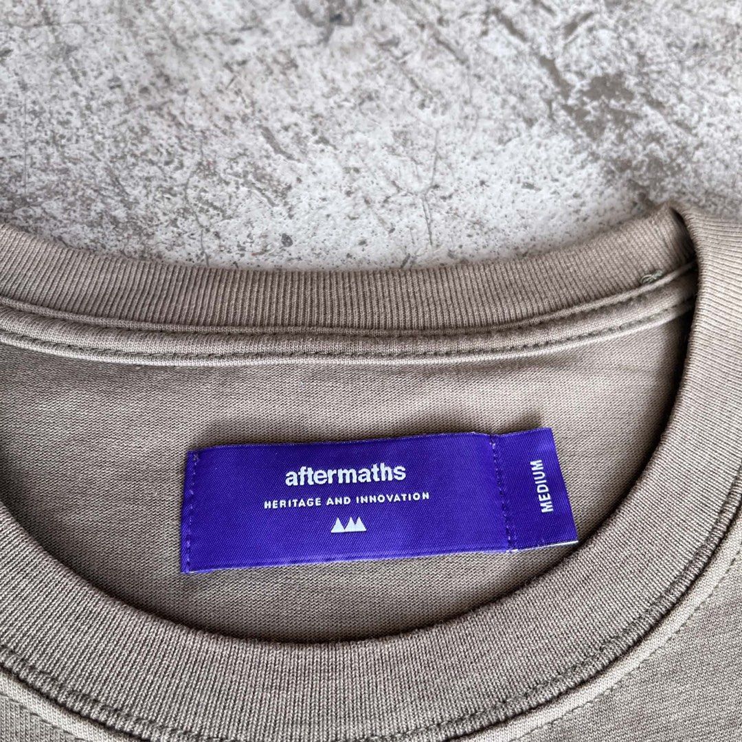 Aftermaths tee (Category: Tshirts & Polo Shirts ) located in Caloocan City. Submitted by landcruiser76__ (Listing ID 1470874134, Image 2). Description: - Brand: Aftermaths - Color: Taupe / Khaki with purple interior neck tag - Size: Medium - Material: Heavyweight cotton with clean construction - Design: Tactical utility chest pocket wrapping around to the back - Details: Features strap webbing and a small logo patch - Cut: Crew neck, short sleeve