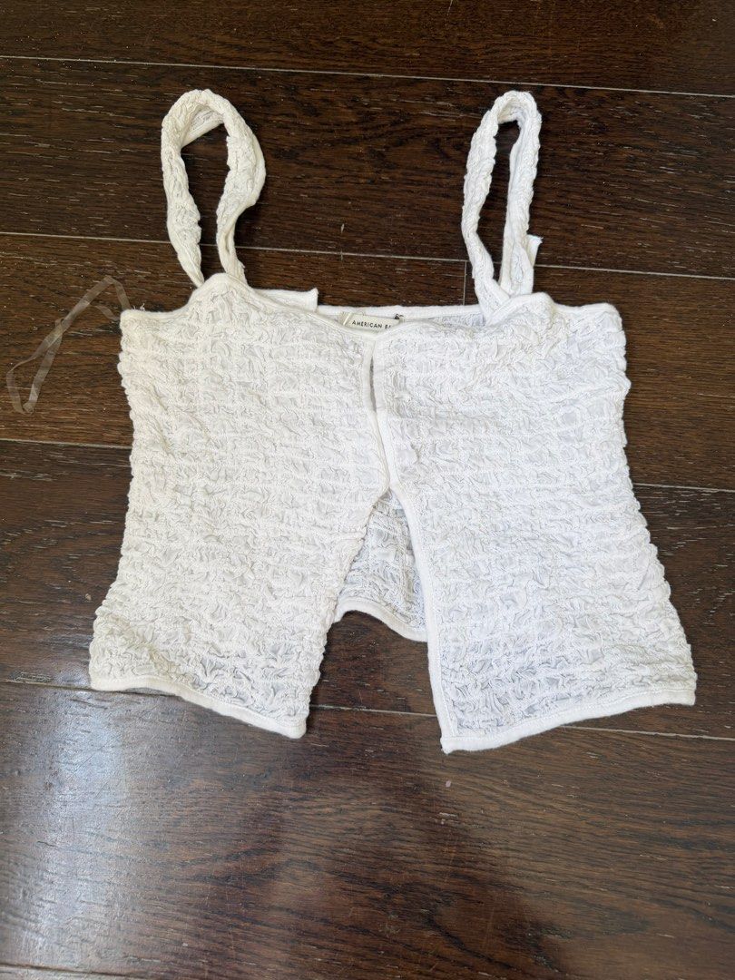 American Eagle White Smocked Crop Top Size XS (Category: Sleeveless) located in Manila. Submitted by shopmnl.studio (Listing ID 1470781510, Image 1). Description: - Brand: American Eagle - Size: XS (Super stretchy material) - Color: White - Details: Textured crinkled fabric, thick straps, split front hem - Style tip: Perfect for pairing with high-waisted jeans or skirts.
