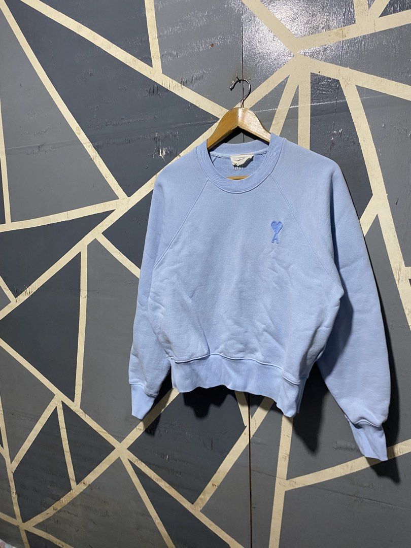 Ami Alexandre Mattiussi Light Blue Sweatshirt (Category: Others Tops) located in Polomolok. Submitted by marrssz (Listing ID 1470744217, Image 2). Description: - Brand: AMI Alexandre Mattiussi - Color: Light Blue - Material: Soft cotton fleece - Design: Crewneck with raglan sleeves - Details: Embroidered blue heart logo on chest and matching AMI lettering at back neckline - Finish: Ribbed collar, cuffs, and hem - Style: Clean look, perfect for ca