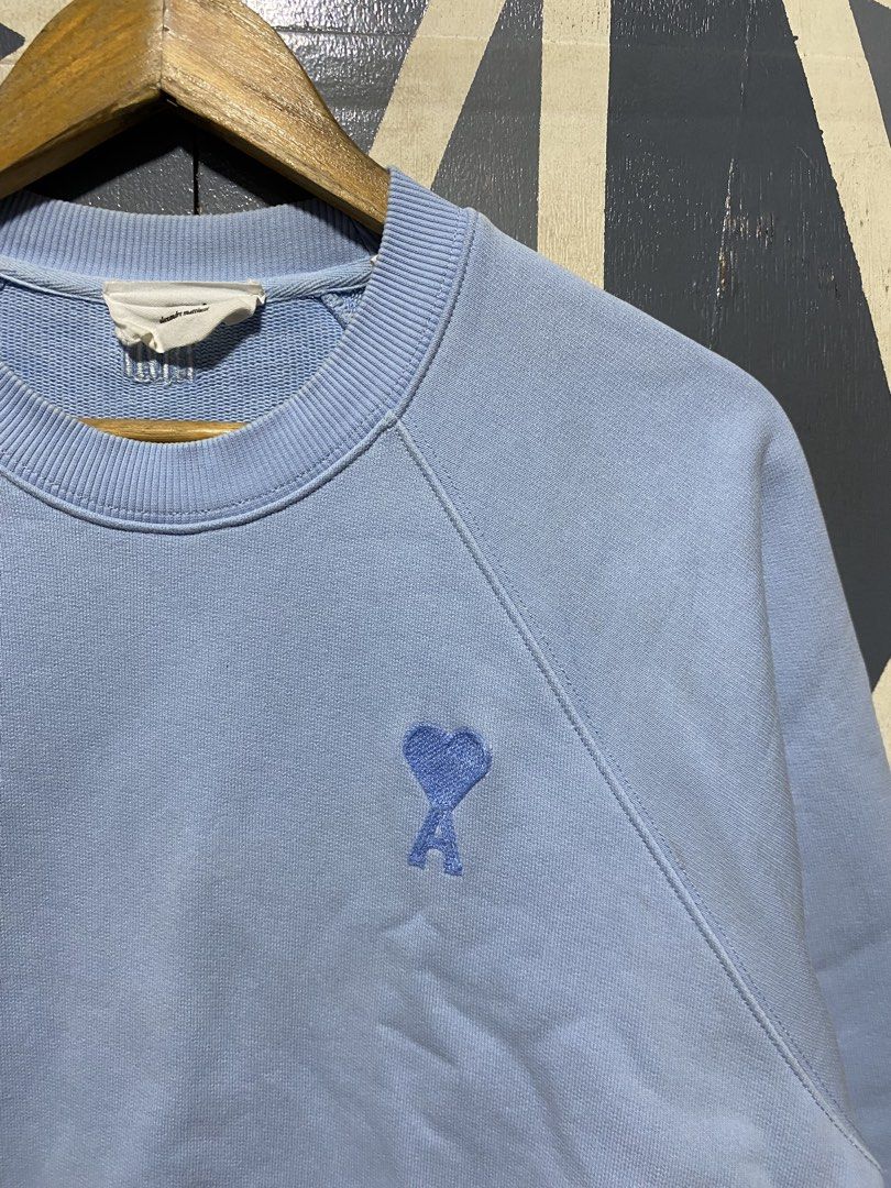 Ami Alexandre Mattiussi Light Blue Sweatshirt (Category: Others Tops) located in Polomolok. Submitted by marrssz (Listing ID 1470744217, Image 3). Description: - Brand: AMI Alexandre Mattiussi - Color: Light Blue - Material: Soft cotton fleece - Design: Crewneck with raglan sleeves - Details: Embroidered blue heart logo on chest and matching AMI lettering at back neckline - Finish: Ribbed collar, cuffs, and hem - Style: Clean look, perfect for ca