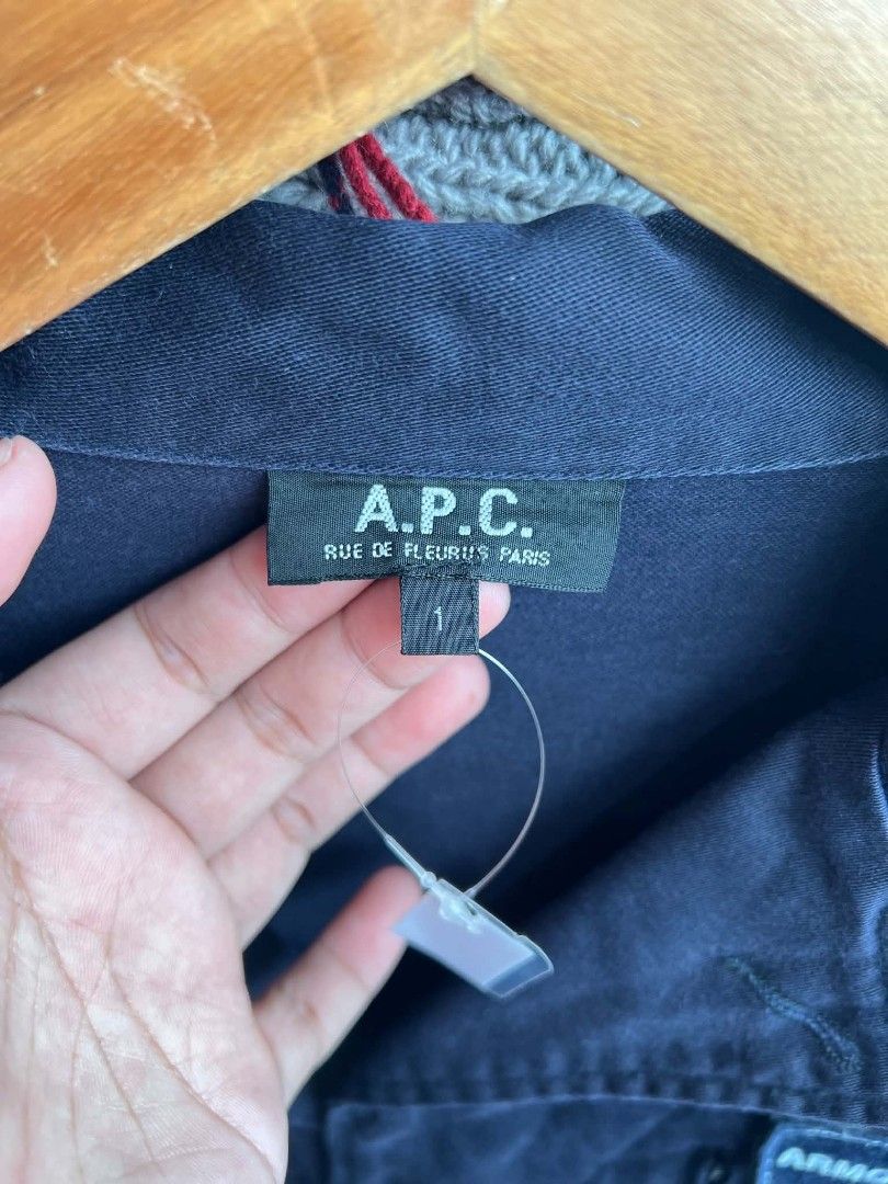 A.P.C. Rue De Fleurus Paris Armour Piercing Clash Jacket (Category: Coats, Jackets and Outerwear) located in Urdaneta. Submitted by jayceegarage (Listing ID 1470882261, Image 3). Description: - Brand: A.P.C. Rue De Fleurus Paris - Color: Dark blue - Size: Tagged Size 1 - Design: Unique 'Armour Piercing Clash' patch sewn on the chest - Pockets: Two vertical zipped chest pockets and two front flap pockets - Closure: Classic button front with collar
