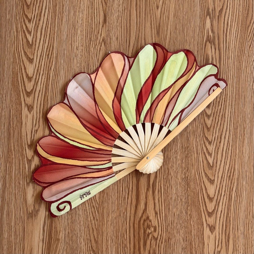Araw Pamaypay Wooden Folding Fan with Abstract Pattern (Category: Other Accessories) located in Calamba. Submitted by quietarchive (Listing ID 1470811302, Image 1). Description: - Soldout on their website - Design: Abstract painted pattern in red, orange, green, and cream with a unique Thai text signature - Material: Sturdy bamboo ribs and handle - Size: Standard hand fan size - Use: Ideal stylish accessory for warm weather or home decor.