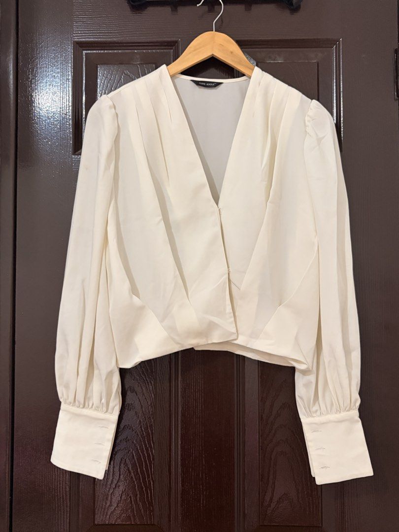 ASM ANNA White Long Sleeve V-Neck Blouse (Category: Longsleeves) located in Marikina City. Submitted by _bananahanaa (Listing ID 1470768381, Image 1). Description: - Brand/Style: ASM ANNA white blouse - Design: Deep V-neck, long bishop sleeves with 3-button cuffs, and front/back pleats - Fit: Cropped style - Flaws: Has a few light yellowish stains near the right shoulder area (see last photo for reference).