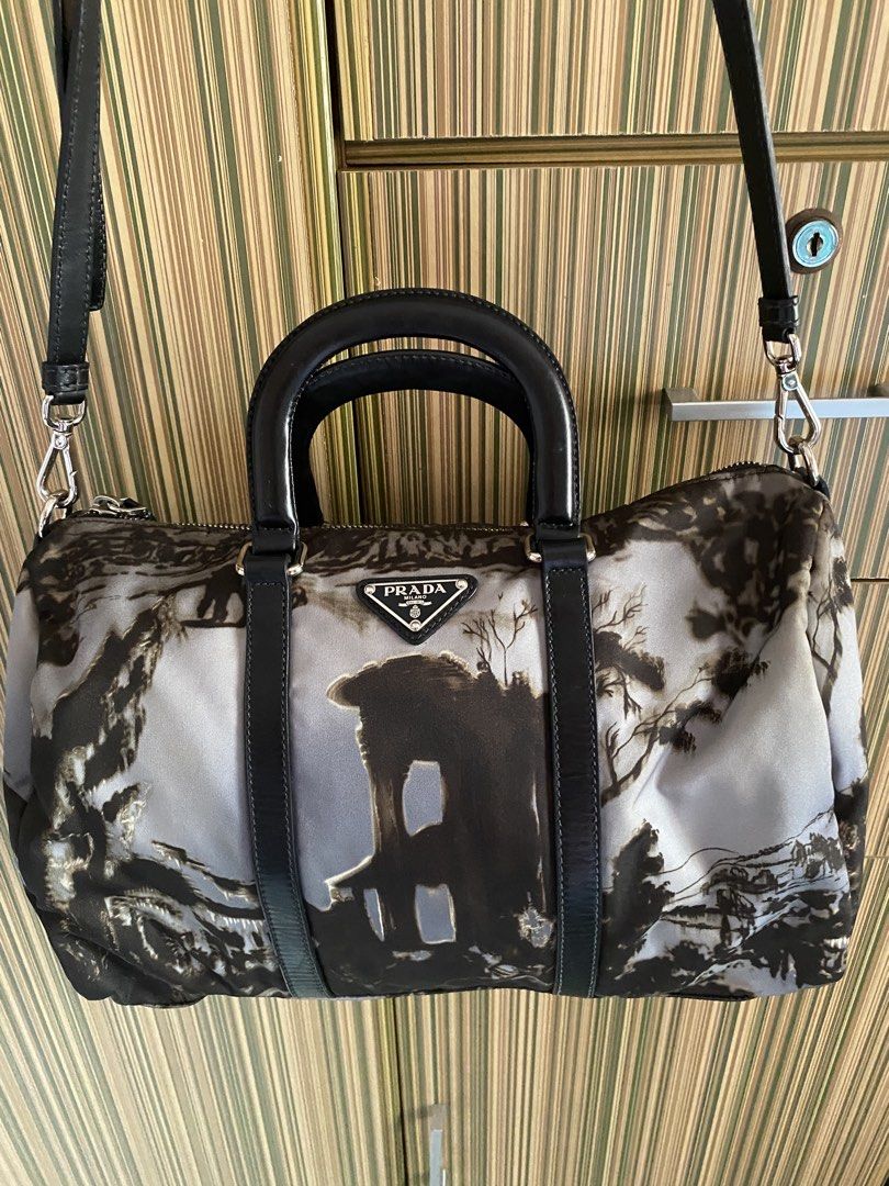 Authentic Prada Landscape Print Nylon Duffle Handbag (Category: Luxury Bags & Wallets) located in Taguig. Submitted by sandzclick (Listing ID 1470766495, Image 1). Description: - Authentic Prada nylon duffle bag in a chic black and grey landscape print - Dual rolled leather top handles and detachable black leather shoulder strap - Silver-tone hardware with metal protective feet on the base - Iconic Prada enamel triangle logo on the front - Secure