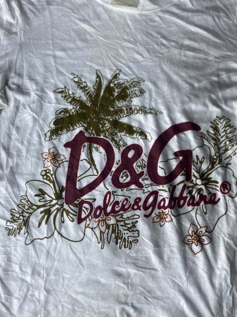 Authentic Y2k D&G Dolce & Gabbana Graphic Tee (Category: Announcements) located in Dagupan City. Submitted by vell25apparel (Listing ID 1470817232, Image 2). Description: - Brand: D&G Dolce & Gabbana - Color: White with large palm tree and floral front graphic - Size: Small (tag and Ittierre distribution label intact) - Details: Ribbed crew neck, short sleeves, and small D&G shoulder loop - Condition: Pre-owned with some yellowing around the coll