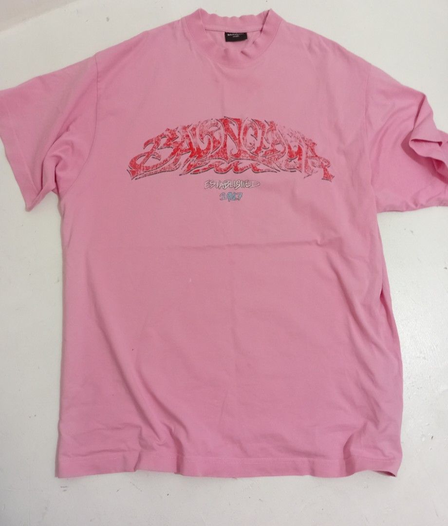 Balen ciaga OffShore OverSized Crew TShirt (Category: Luxury Apparel) located in Navotas City. Submitted by ms.soulana (Listing ID 1470864613, Image 2). Description: PreOwned Lightly Used Balenciaga Pink with red graffiti print OverSized Crew TeeShirt XS on Size tag fits up to XlL - Design: "Balenciaga Established 1917" graphic across the chest - Fit: Relaxed crewneck, short sleeves, oversized style - Condition: Clean fabric, graphic print is int