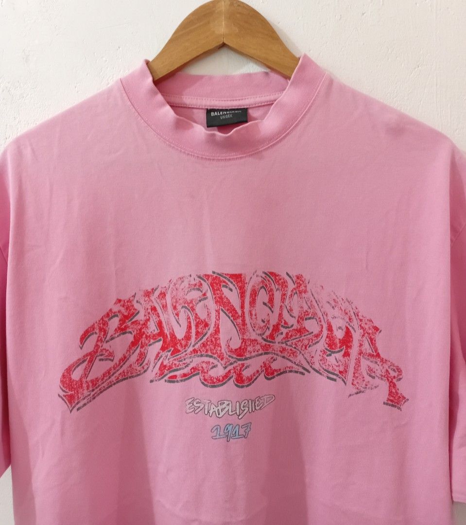 Balen ciaga OffShore OverSized Crew TShirt (Category: Luxury Apparel) located in Navotas City. Submitted by ms.soulana (Listing ID 1470864613, Image 3). Description: PreOwned Lightly Used Balenciaga Pink with red graffiti print OverSized Crew TeeShirt XS on Size tag fits up to XlL - Design: "Balenciaga Established 1917" graphic across the chest - Fit: Relaxed crewneck, short sleeves, oversized style - Condition: Clean fabric, graphic print is int