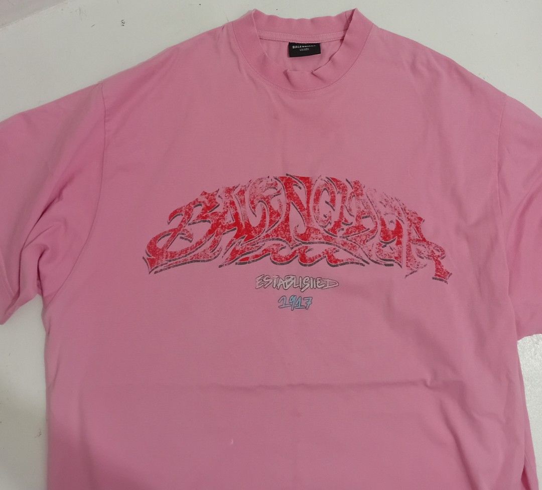 Balen ciaga OffShore OverSized Crew TShirt (Category: Luxury Apparel) located in Navotas City. Submitted by ms.soulana (Listing ID 1470864613, Image 1). Description: PreOwned Lightly Used Balenciaga Pink with red graffiti print OverSized Crew TeeShirt XS on Size tag fits up to XlL - Design: "Balenciaga Established 1917" graphic across the chest - Fit: Relaxed crewneck, short sleeves, oversized style - Condition: Clean fabric, graphic print is int