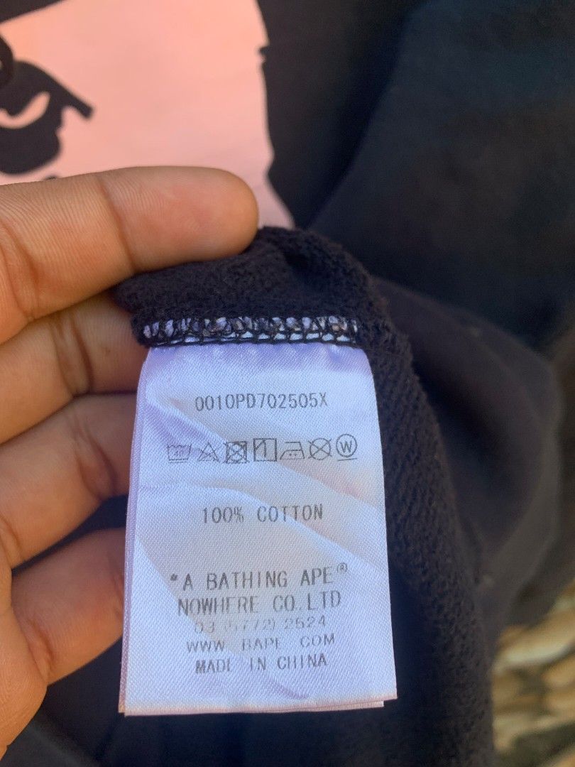 BAPE Pink Ape Head Ladies (Category: Coats, Jackets and Outerwear) located in Aloran. Submitted by chester78864 (Listing ID 1470931181, Image 3). Description: - Brand: A Bathing Ape (BAPE) - Item: Black Hoodie - Size: Small - Design: Large pink ape head graphic with "By Bathing Ape" text on the chest - Features: Kangaroo pocket, drawstrings with branded metal aglets - Details: Includes original interior neck tags and wash tags showing product cod