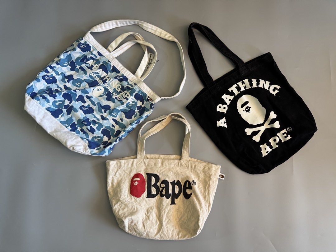 BAPE Tote Bag Bundle Set of 3 (Category: Tote Bags) located in Baguio. Submitted by stockedclothing047 (Listing ID 1470756790, Image 1). Description: BATHING APE CANVASS TOTE BAGS BALE BLUE CAMO 2180 (NEEDS CLEANING) BAPE PIRATE BLACK 1580 BAPE WHITE SPELLOUT 1380 4.5k AS PACK (PRIO) - 3-Piece BAPE Tote Bag Bundle - Blue camo shoulder bag with white base - Black canvas tote featuring iconic ape head and crossbones graphic - Cream-colored tote wit