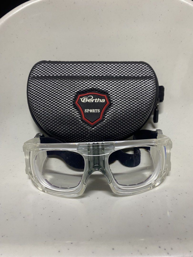 Bertha Sports Protective Goggles with Hard Case (Category: Sunglasses & Eyewear) located in Pasacao. Submitted by wengpullar37205 (Listing ID 1470926948, Image 1). Description: Clear protective sports eyewear by Bertha. Sturdy transparent frame with cushioned inner nose bridge and rubber grip areas on the sides. Adjustable black elastic strap ensures a secure fit during active games. Includes a matching zippered hard shell case with a patterned m