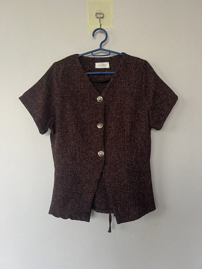 BETTY Brown Short Sleeve Button Top with Tie Back (Category: Blouses) located in San Fernando. Submitted by wearvfs (Listing ID 1470887584, Image 1). Description: - Brand: BETTY - Color: Brown textured - Neckline: V-neck with 3 gold-tone decorative buttons - Fit: Self-tie ribbon at the back waist for a cinched look - Sleeves: Short sleeves - Material: Lightweight and comfortable - Size/Measurement: Pit to pit approx. 44 cm - Condition: Great, wel