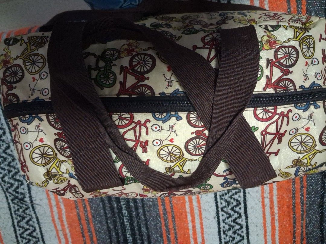 Bicycle Pattern Travel Duffel Bag with Shoulder Strap (Category: Shoulder Bags) located in Angeles City. Submitted by anneps (Listing ID 1470856257, Image 3). Description: - Design: Cream duffel with a vibrant, colorful bicycle print and brown carrying handles - Versatile Carry: Includes an adjustable and detachable shoulder strap for convenience - Interior: Roomy black fabric lining featuring a secure zipped side pocket - Size: Measures roughly 