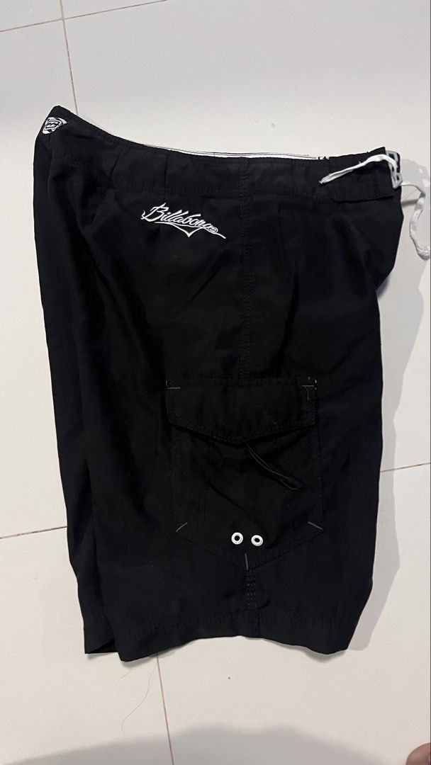Billabong Black Board Shorts Size 32 (Category: Swim Trunks & Board Shorts) located in Manila. Submitted by wildfire-06ed46 (Listing ID 1470879199, Image 1). Description: - Brand: Billabong - Color: Solid Black - Size: 32 - Material: 100% Polyester - Closure: Drawstring waist - Pockets: Side cargo pocket with buttonhole drain holes - Details: Embroidered brand logos on leg and back waistband - Care: Machine washable.