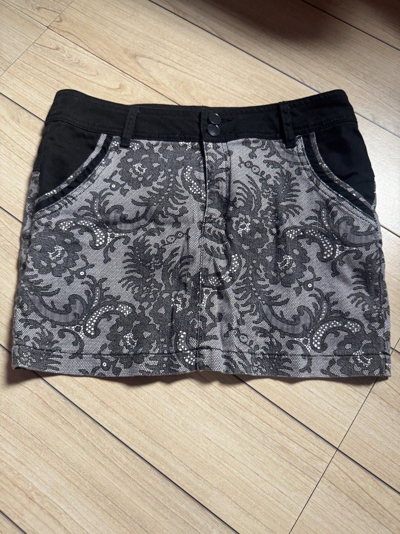 Black and White Lace Pattern Mini Skirt (Category: Skirts) located in Malabon City. Submitted by nanayinah (Listing ID 1470790701, Image 1). Description: - Black and white patterned mini skirt with intricate lace-like floral details - Features a solid black waistband and pocket trim for contrast - Front double button closure - Slim fit style with a short length - Versatile piece that is easy to pair with any plain top - No brand tags visible.
