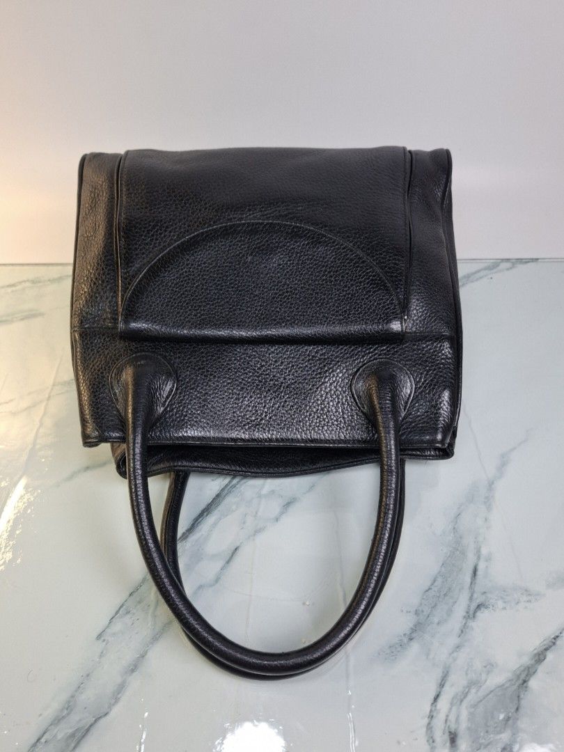 Black Leather Handbag with Front Flap Pocket (Category: Tote Bags) located in Pasay City. Submitted by onick_79 (Listing ID 1470919369, Image 3). Description: - Material: Premium black pebble grain leather -Dimensions: L 30 x H 26 x W 10 cm - Design: Structured shape with solid hardware - Carry: Comfortable dual top handles - Storage: Front flap compartment with magnetic snap closure and back exterior zipper pocket - Interior: Clean and spacious 